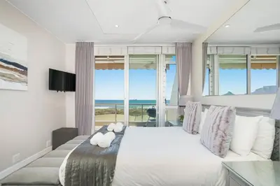 a bedroom with a large white bed with a large window at Dolphin Beach H106 in Bloubergstrand