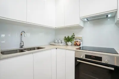 a white kitchen with a sink and a stove at Dolphin Beach H106 in Bloubergstrand