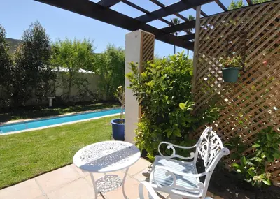 a patio with a table and chairs next to a pool at The Gables Hermanus in Hermanus