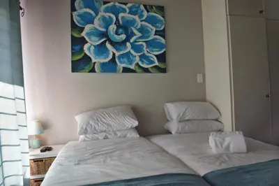 a bedroom with two beds and a painting on the wall at Zonnevanger Guesthouse in Noorder-Paarl