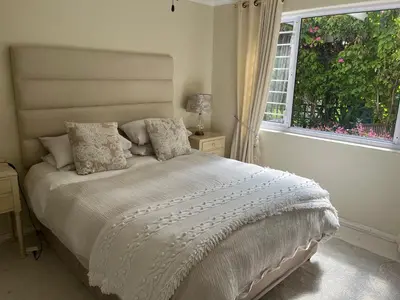 a bedroom with a white bed with a window at On Broadwalk Cottage in Cape Town