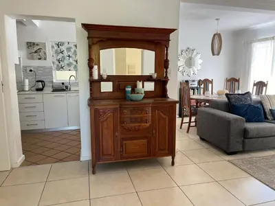 a living room with a wooden dresser with a mirror at On Broadwalk Cottage in Cape Town