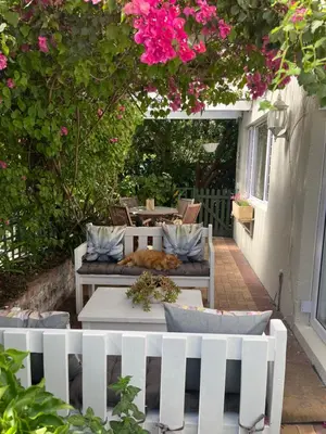 a patio with a white fence and pink flowers at On Broadwalk Cottage in Cape Town