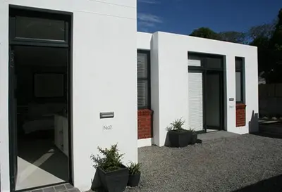 a white house with black doors and potted plants at No. 9 Keurboom in Cape Town