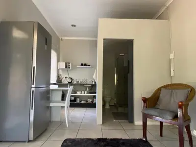 a kitchen with a refrigerator and a chair and a table at Willows Curve in Somerset West