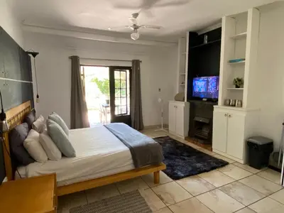 a bedroom with a large bed and a television at Willows Curve in Somerset West