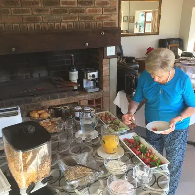 a woman standing in a kitchen preparing food at Paarl Mountain Lodge in Paarl