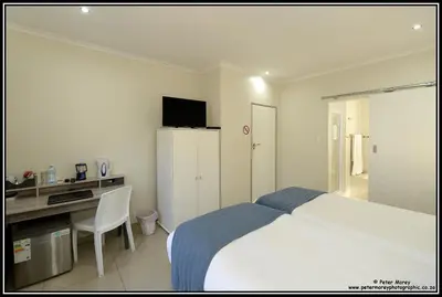 a bedroom with a bed and a desk with a computer at Paarl Mountain Lodge in Paarl
