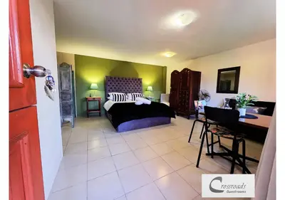 a bedroom with a bed and a desk in a room at Crossroads Guestrooms in Gordonʼs Bay