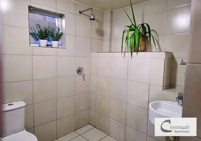 a bathroom with a toilet and a sink with potted plants at Crossroads Guestrooms in Gordonʼs Bay