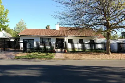 a white house with a black fence and a tree at 9 on Drommedaris in Stellenbosch