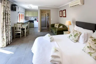 a bedroom with a large white bed and a kitchen at Summerhill Guest Farm in Worcester