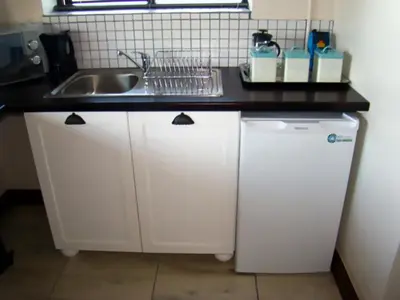 a kitchen with a sink and a white refrigerator at Zamar Guest House in Caledon