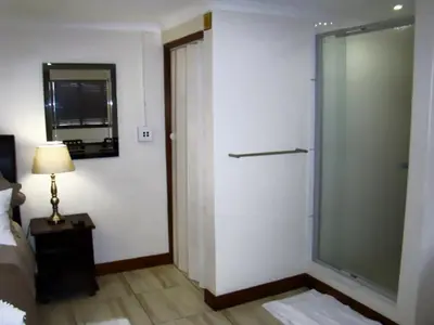a bedroom with a glass shower door next to a bed at Zamar Guest House in Caledon