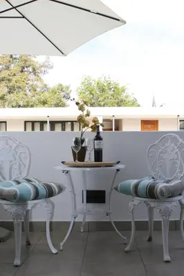 a table and chairs on a patio with a white wall at Avemore Eikehoff No 26 full power back up in Stellenbosch