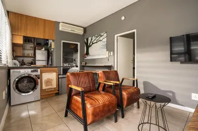 a kitchen with two chairs and a washing machine at Avemore Eikehoff No 26 full power back up in Stellenbosch