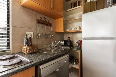 a small kitchen with a refrigerator and a sink at Avemore Eikehoff No 26 full power back up in Stellenbosch