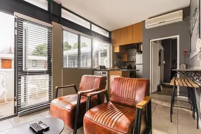 a living room with two chairs and a kitchen at Avemore Eikehoff No 26 full power back up in Stellenbosch