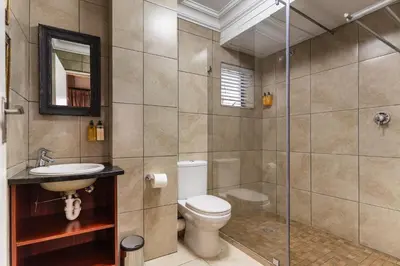 a bathroom with a toilet and a glass shower at Avemore Eikehoff No 26 full power back up in Stellenbosch