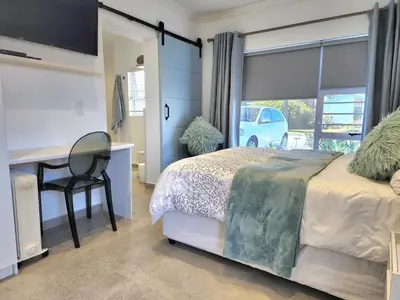 a bedroom with a bed and a desk and a window at Mossel 11 Studio in Bloubergstrand