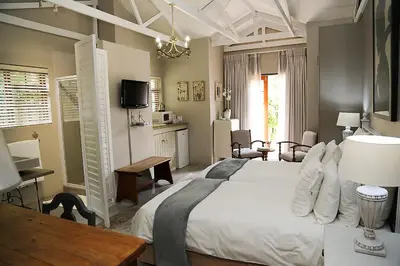 a bedroom with a large white bed and a table at 5 Konings Guesthouse in Paarl
