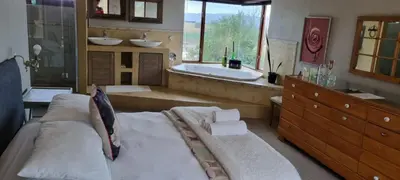 a large bathroom with a large bed and a bath tub at Die Pastorie in Caledon