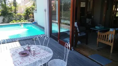 a table and chairs next to a swimming pool at Die Pastorie in Caledon