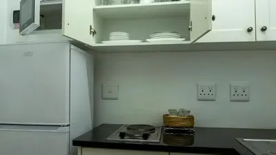 a kitchen with white cabinets and a stove top oven at Eastcliff Cottage in Hermanus