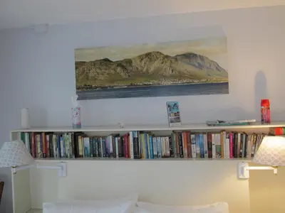 a book shelf filled with books and a painting on a wall at Casa Del Mar in Hermanus
