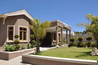 a house with a green yard in front of it at Berg en Dal Guesthouse in Villiersdorp