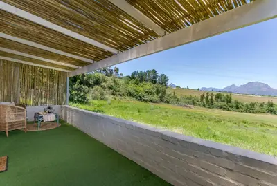 an outdoor patio with green grass and mountains in the background at Wildlife Retreat on a Wine-Farm in Stellenbosch