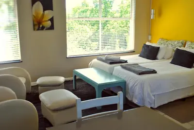 a room with two beds and a table and chairs at BlackHorse Accommodation in Stellenbosch