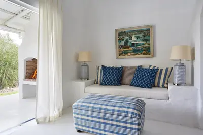 a white living room with a couch with blue pillows at La Cotte Forest Cottages in Franschhoek