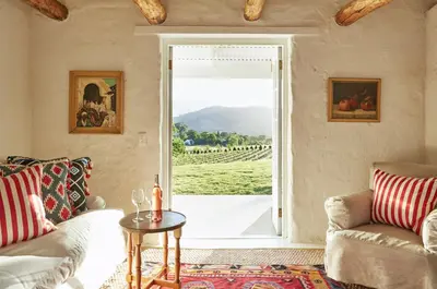 a living room with a couch and a table and a window at La Cotte Forest Cottages in Franschhoek