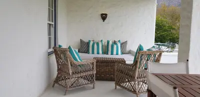 a porch with two chairs and a table with pillows at La Cotte Forest Cottages in Franschhoek