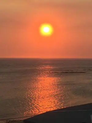 a sunset over the ocean with the sun in the sky at Pebble Moon Holiday Flat in Strand