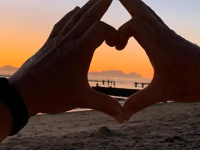a pair of hands making a heart on the beach at Pebble Moon Holiday Flat in Strand