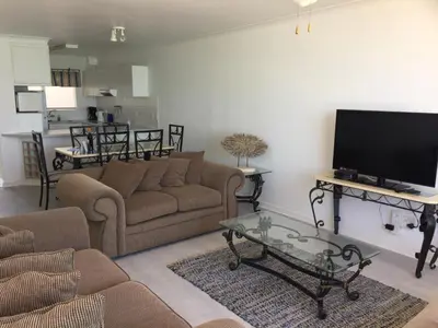 a living room with a couch and a flat screen tv at Pebble Moon Holiday Flat in Strand