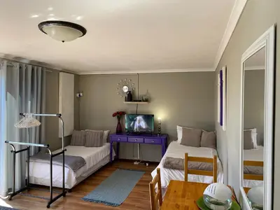 a living room with two beds and a tv at Azura Sleep Brackenfell in Brackenfell