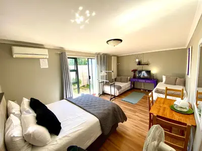 a bedroom with a bed and a living room with a table at Azura Sleep Brackenfell in Brackenfell