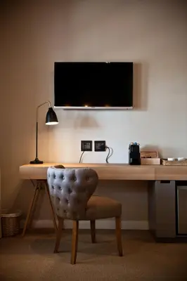 a desk with a chair and a television on a wall at d'Olyfboom Guest House B & B in Paarl