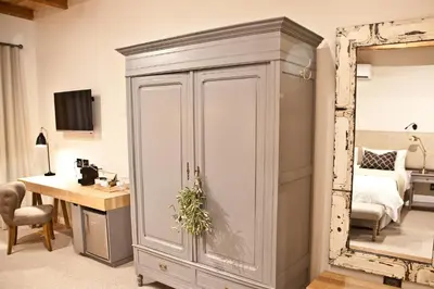 a room with a cupboard and a desk and a bedroom at d'Olyfboom Guest House B & B in Paarl