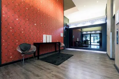 a lobby with a red wall with a table and a chair at Manhattan Towers 507 by CTHA in Cape Town