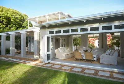 a covered patio with white furniture on a house at Vivere in Hermanus