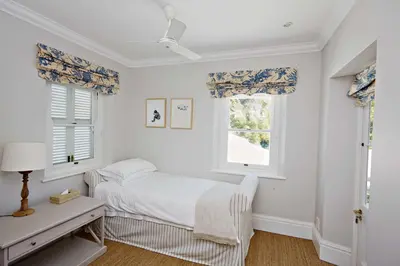 a white bedroom with a bed and two windows at Vivere in Hermanus