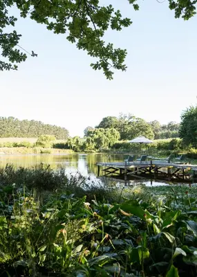 a dock on a river with a table and chairs at Vredenhof Farm Cottage in Elgin