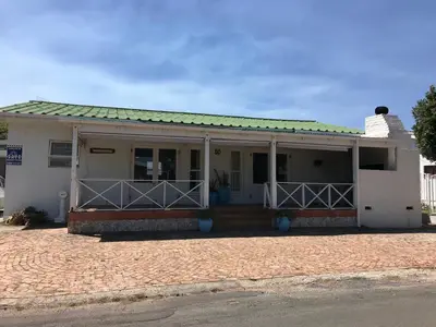 a white house with a porch and a driveway at Leisure By The Sea in Kleinmond
