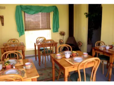 a dining room with wooden tables and chairs at Blue Mountain Guest House in Bloubergstrand