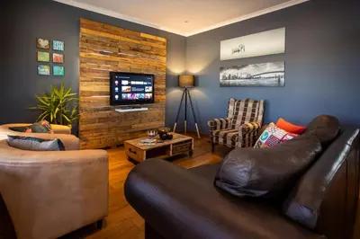 a living room with a leather couch and a tv at Modern Shabby Chic Apartment in Durbanville