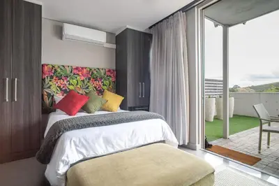 a bedroom with a large bed and a balcony at Lux Andringa Walk Apartments in Stellenbosch